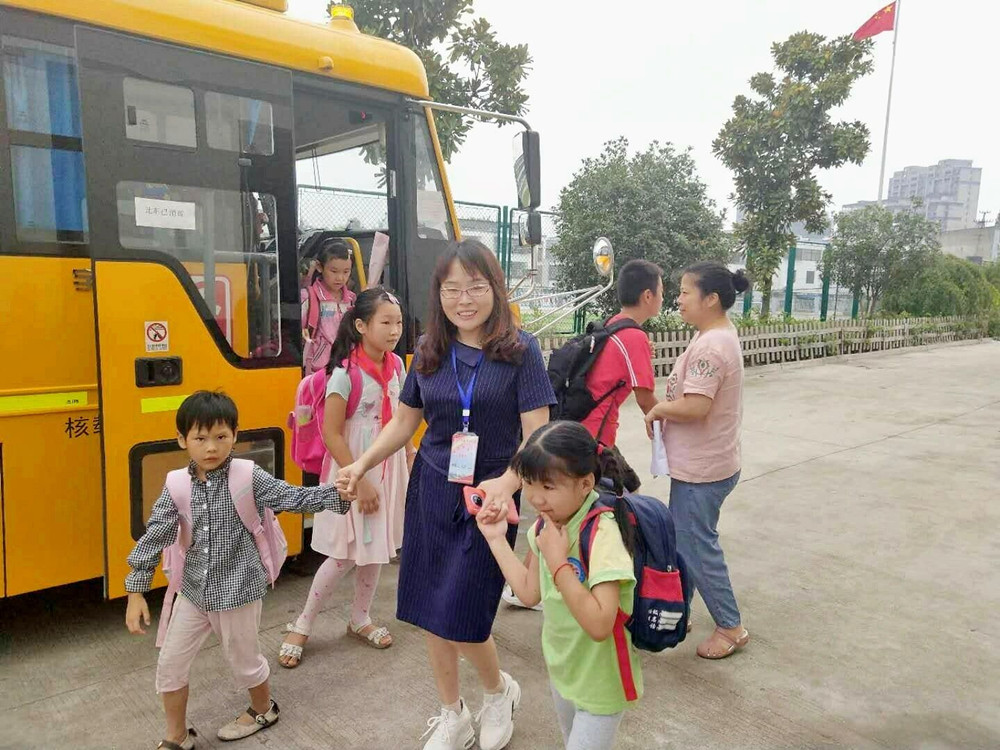圖為校車照管員阿姨護送孩子上下學。