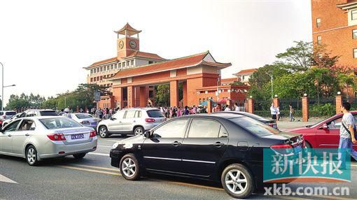 學(xué)校門口的路段停滿前來接送孩子的車輛,不少家長在校門口等候。